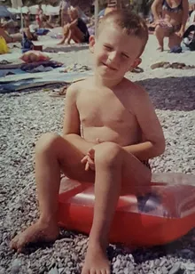 Mihail as a child on a pebble beach, chest already showing the dip